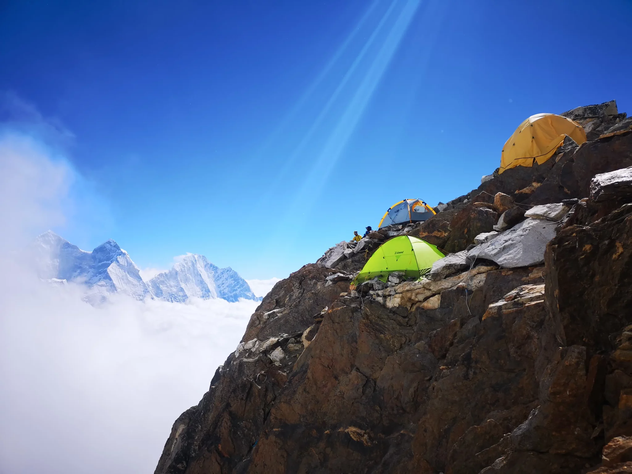 Tents set up on rocky slope at Camp 2 on Ama Dablam with snowy Himalayan peaks in background