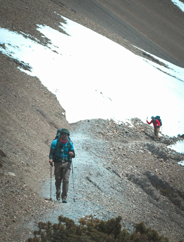 Two people walking up a mountain trail

