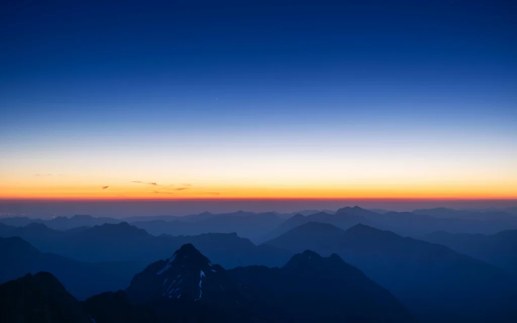 The sun sets over the mountains in this photo
