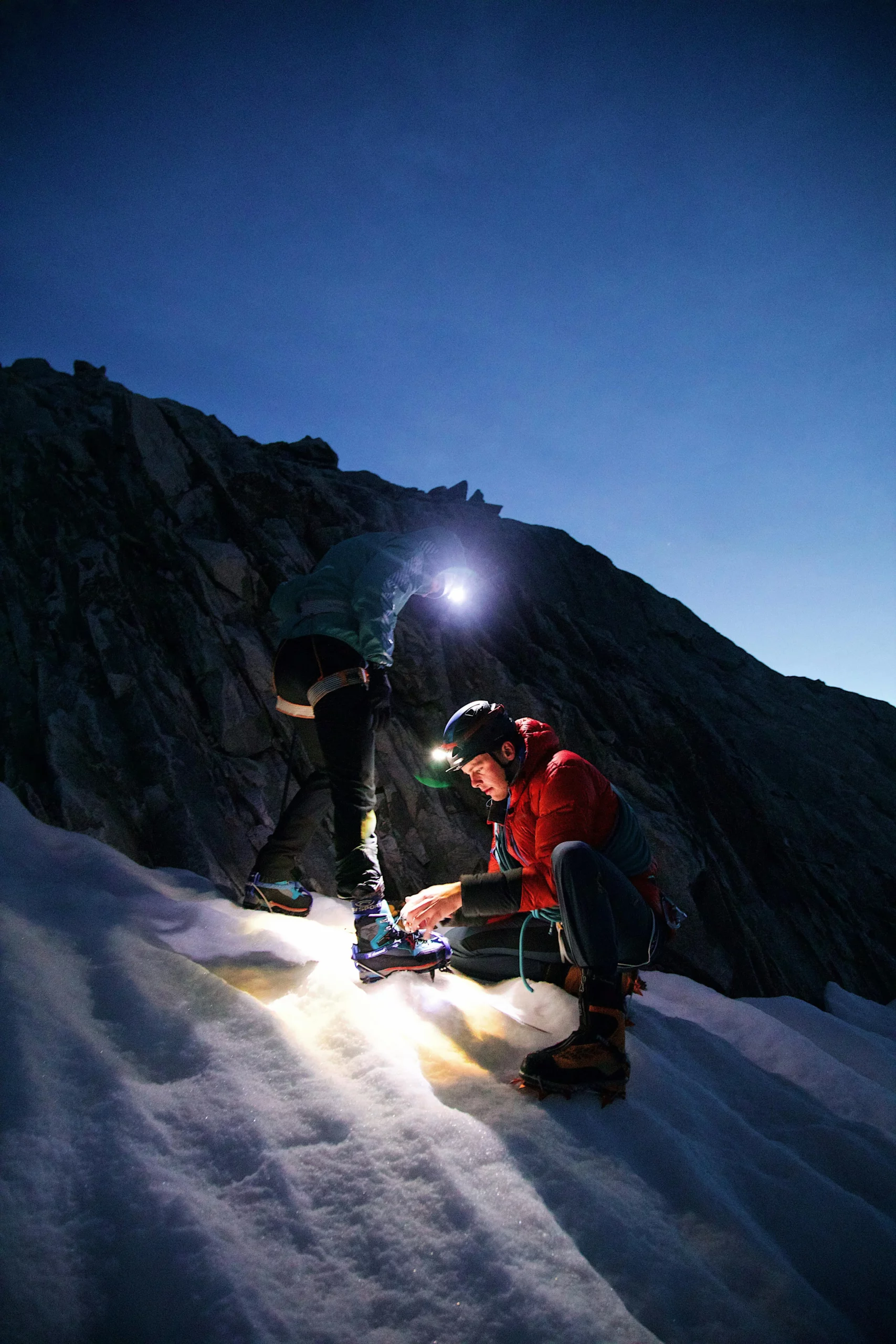 Two people on the side of a mountain with a light