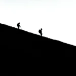 Silhouettes of Climbers Walking Down the Hill