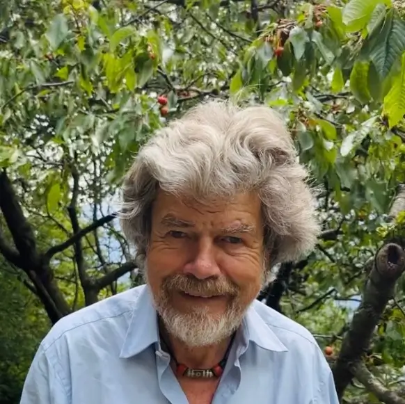 photo of Reinhold Messner, with grey hair and blue tshirt and smiling face look to camera