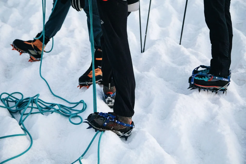 A group of people wearing snow shoes and climbing ropes
