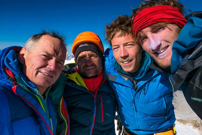 ow-covered twin peaks of Nanda Devi and Nanda Devi East (Sunanda Devi) rising above a dark silhouette of forested ridges, with morning light highlighting the steep faces.