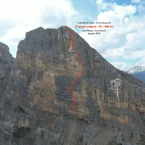 A rugged mountain cliff in the Dolomiti di Fanes, Furcia Rossa III, with an orange dashed line marking a climbing route labeled "il tempo sospeso - IX / 300 mt." The route is credited to Leo Gheza and Luca Ducoli, dated August 2025, under clear skies with some clouds.